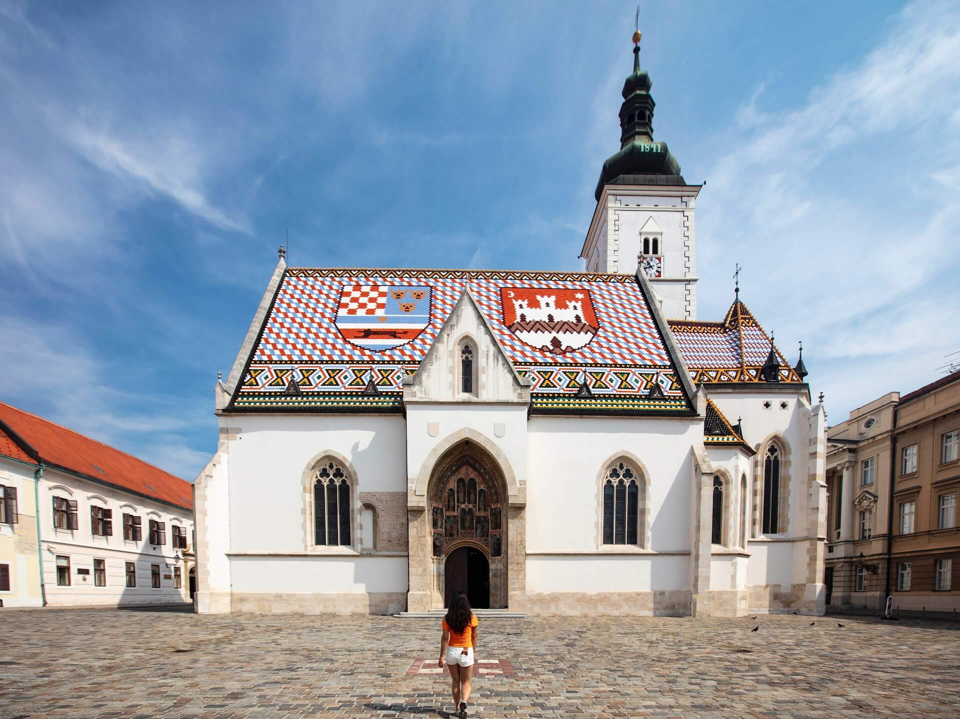 A person standing in front of a white building with a red roof